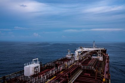 Vista aérea de um grande navio cargueiro navegando em mar aberto sob céu parcialmente nublado.