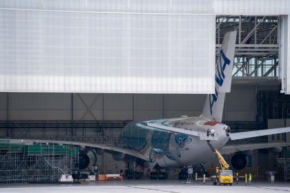 Avião de grande porte em manutenção dentro de um hangar.